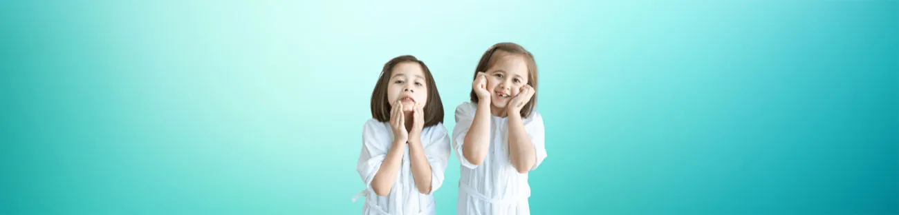 Pediatric Dentistry in London Ontario | Fairmont Dental Centre Two smiling young girls posing with hands on cheeks during pediatric dentistry visit at Fairmont Dental Centre in London Ontario